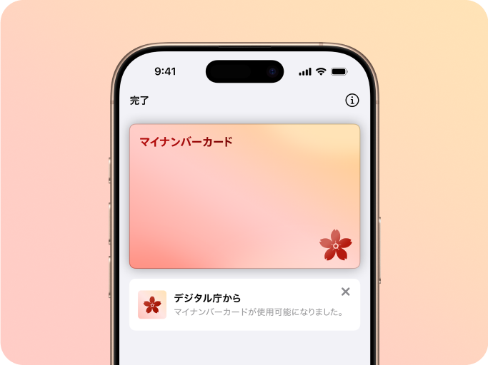 「iPhoneのマイナンバーカード」の画像。iPhoneの画面のなかに、桜色のマイナンバーカードのイメージが表示されている。カードの左上には「マイナンバーカード」の文字が書かれ、右下には桜のイラストが描かれている。