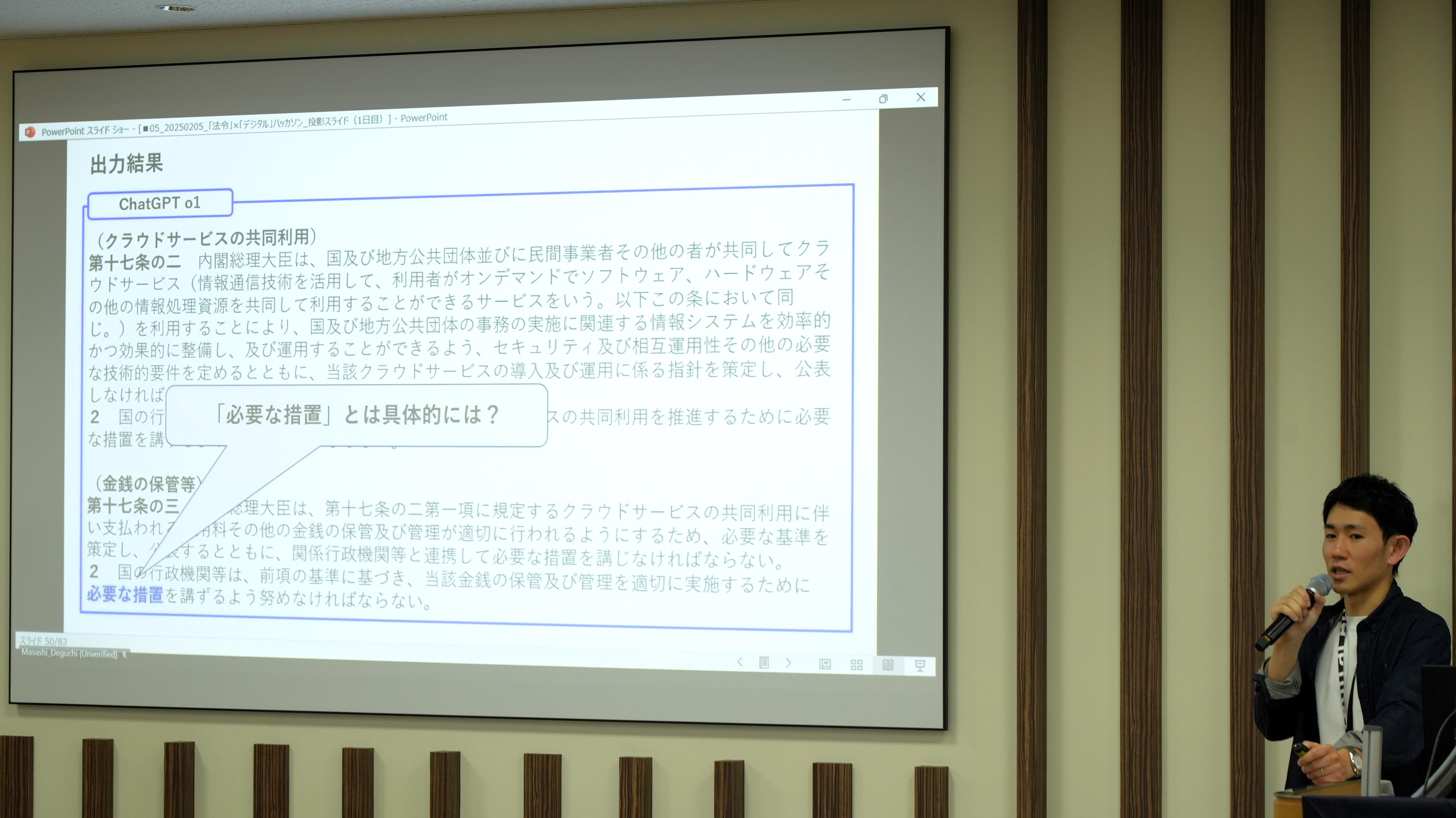 デジタル庁の上田弁護士が取組を紹介している様子。上田弁護士の横にあるスクリーンには、生成AIによる出力結果の例が投影されている。