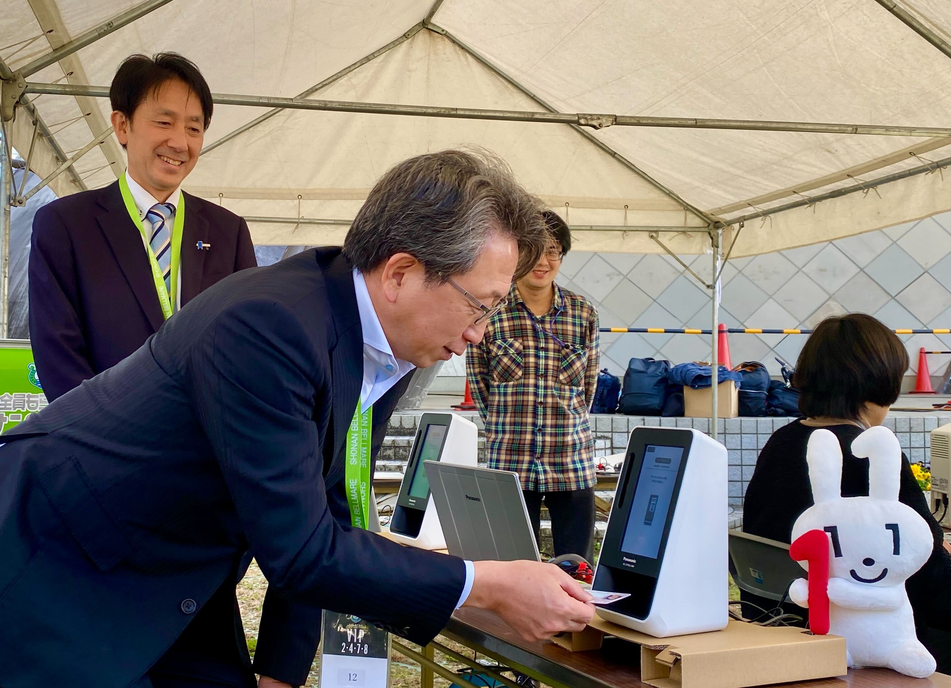 Mr. Taira, Minister for Digital Transformation, experiencing identity verification by My Number Card using facial recognition terminals