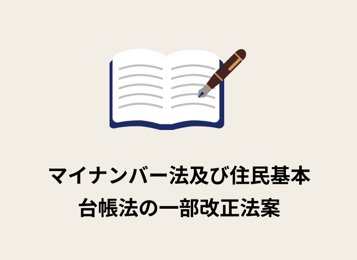 ベージュの背景に開かれたノートとペンが描かれており、ペンで文字を書いたイラストが挿入され、その下には黒字で「マイナンバー法及び住民基本台帳法の一部改正法案」と書かれた画像